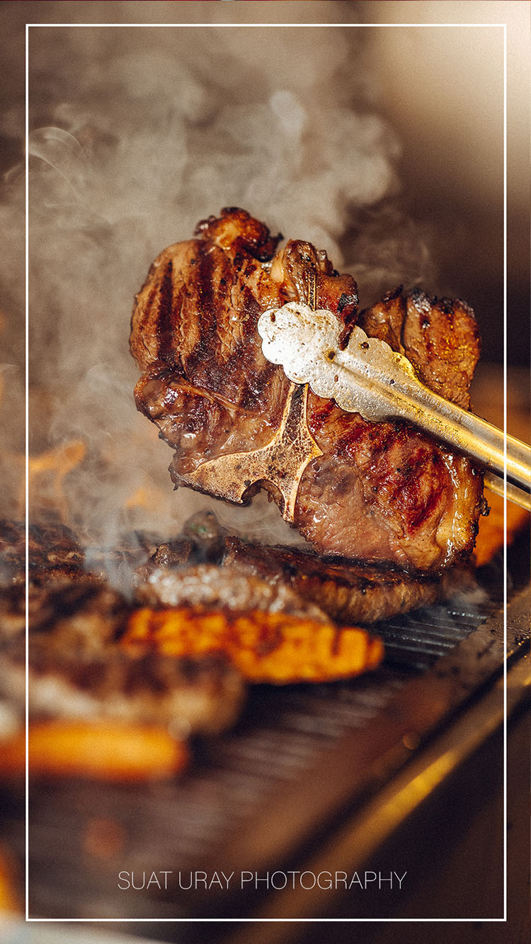 Sfeervolle foodfoto van gegrild vlees met warme tonen, rookaccenten en natuurlijke belichting.