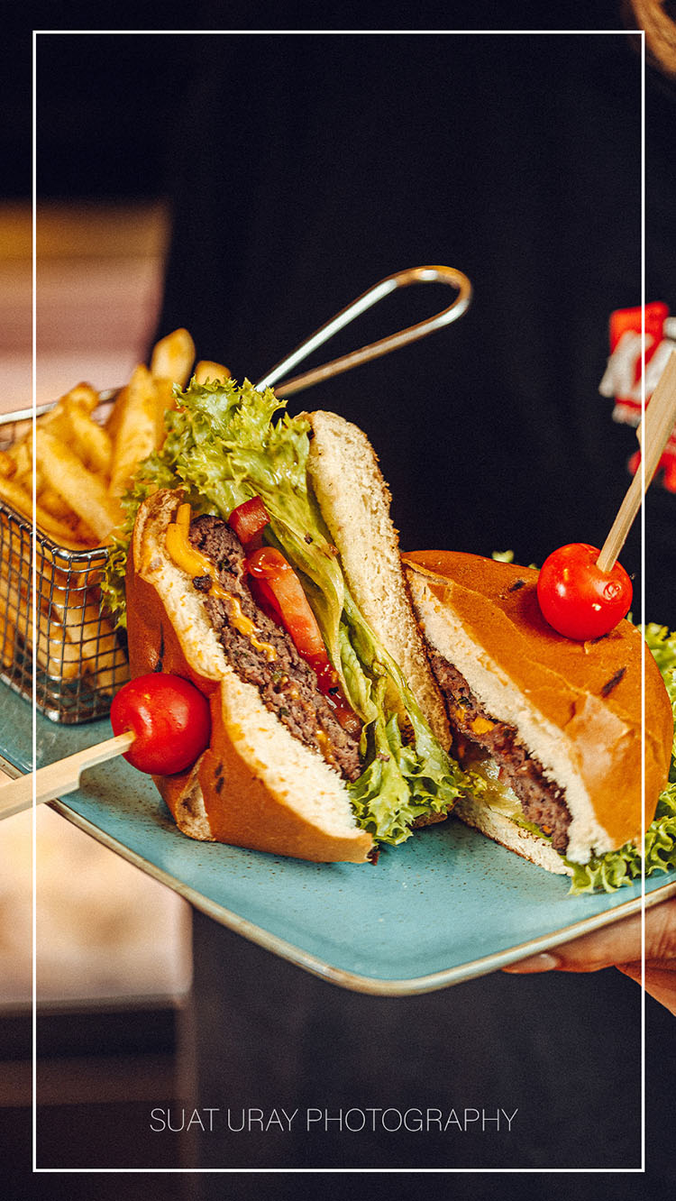 Sfeervolle foodfoto van een ambachtelijke hamburger met natuurlijke belichting en rijke texturen.