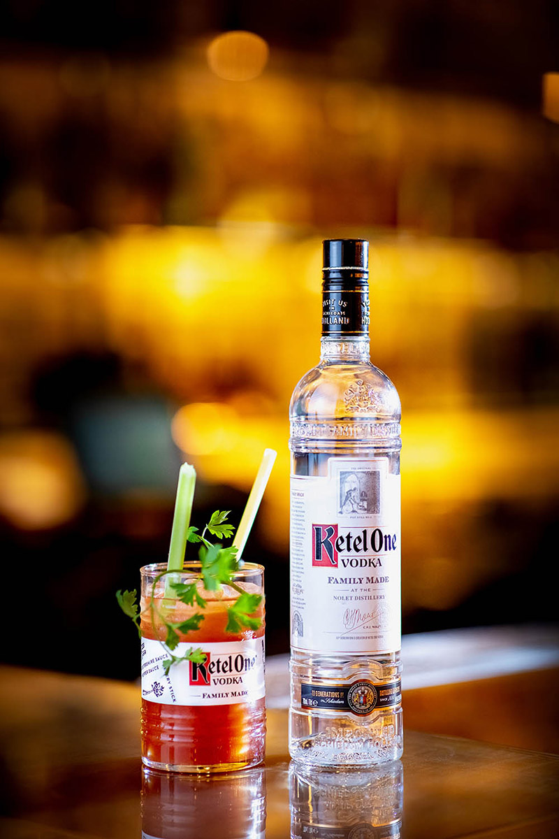 Sfeervolle foto van een Bloody Mary cocktail gemaakt met Ketel One Vodka, gestyled met frisse garnituren en warme belichting.